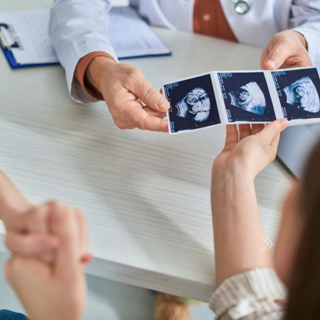 A couple reviewing IVF ultrasound photos with a doctor.